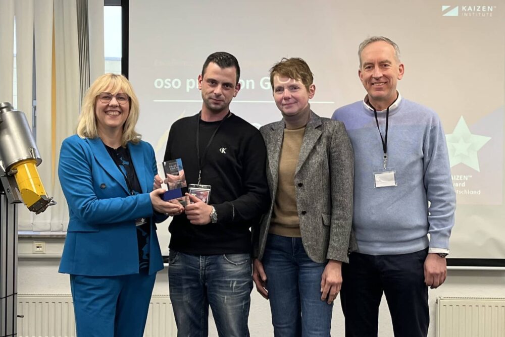 Carmen Beernaert vom KAIZEN Institute überreicht den Award an Dennis Funke, Sabine Schwarz und Horst Kellermann von oso precision (v.l.n.r.).
