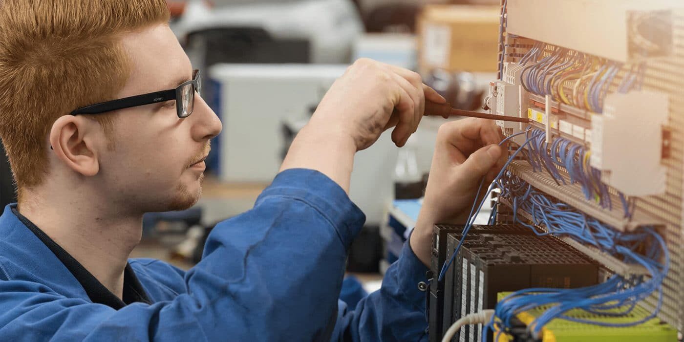 mitarbeiter am elektrokasten kabel schraubendreher in der hand